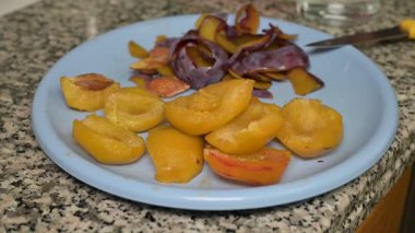 Ev yapımı meyve hazırlama sırasında granit mutfak tezgahında bıçakla dilimlenmiş ve soyulmuş erikler..