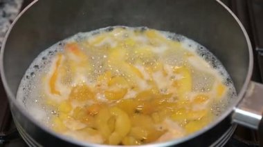 Şeftali dilimleri, ev yapımı şurup hazırlama sırasında gaz sobasında tencerede kaynıyor..