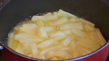 Çiğ patates kızartması kızgın yağda kızartılıyor.