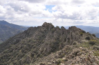 Kıbrıs 'ta dramatik bulutlar ve vahşi Akdeniz arazisiyle kayalık dağ sırtı manzarası