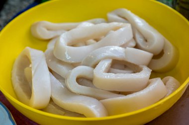 Ham mürekkep balığı sarı bir kâsede yüzüyor.