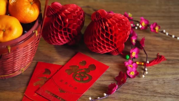 みかんのバスケットと中国の旧正月の祭りの装飾 赤いパケット 梅の花 赤の背景にインゴットとランタン — ストック動画
