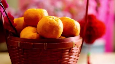 Bir sepet mandalina ve Çin Yeni Yıl Festivali süslemeleri, kırmızı paket, erik çiçeği, Ingot ve kırmızı arka planda fener..