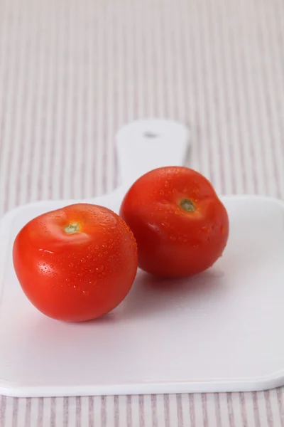 Tomates na tábua de cortar — Fotografia de Stock