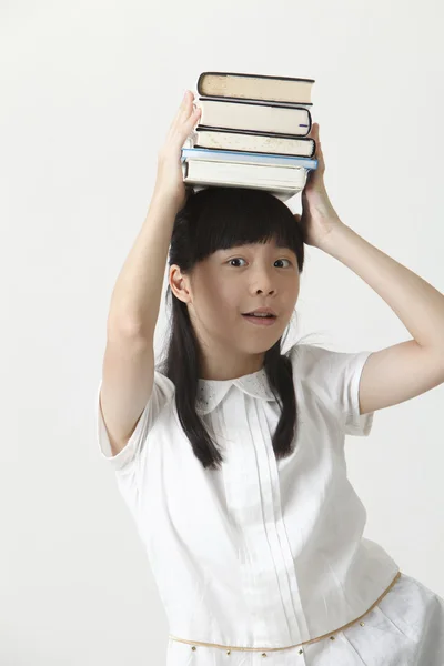 Chica con libros en la cabeza — Foto de Stock