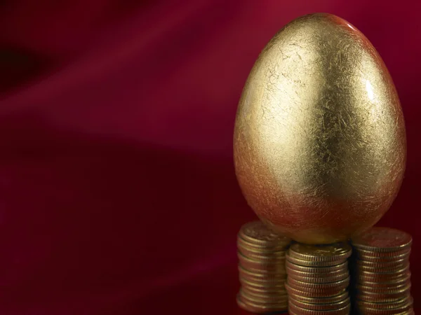 Золотое яйцо на пачке монет — стоковое фото