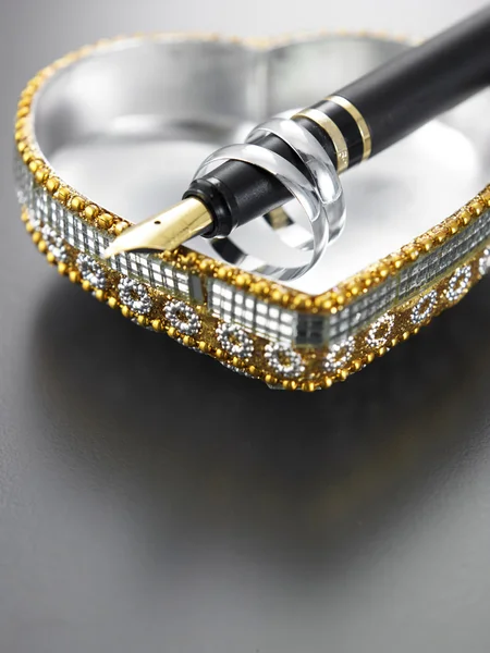 Anéis, caneta e caixa de forma do coração — Fotografia de Stock