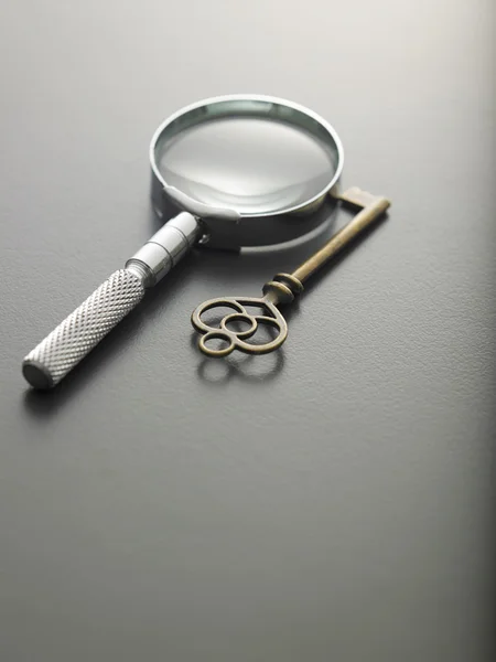 Magnifying glass and a key — Stock Photo, Image