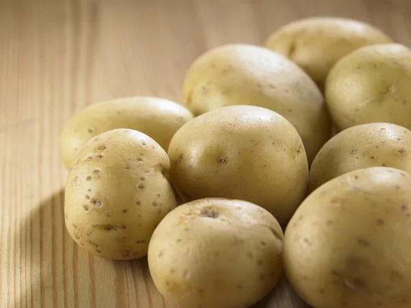 Potatoes on wooden table — Stock Photo, Image