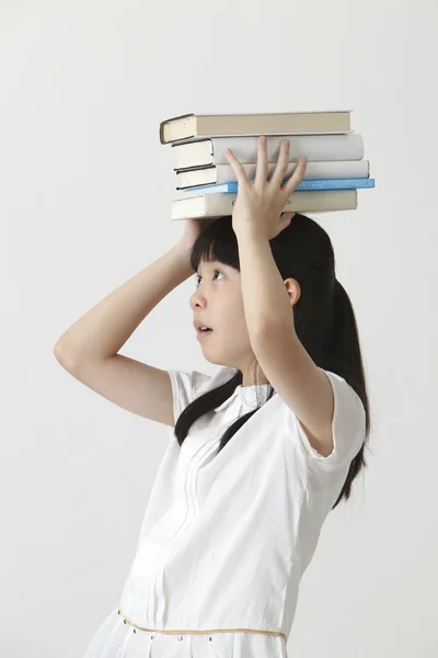 Meisje met boeken op haar hoofd — Stockfoto