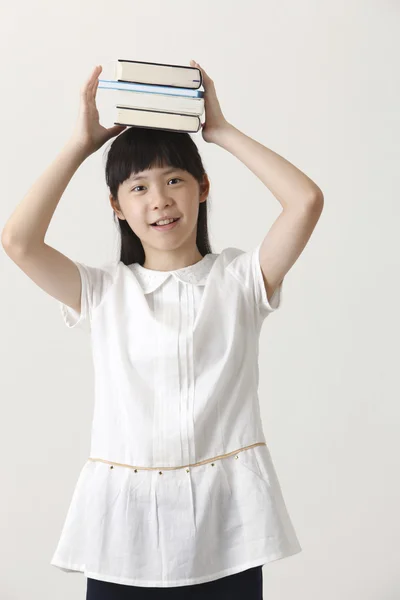 Meisje met boeken op haar hoofd — Stockfoto