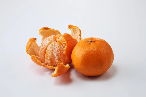 Hele en geschilde mandarijnsinaasappelen — Stockfoto