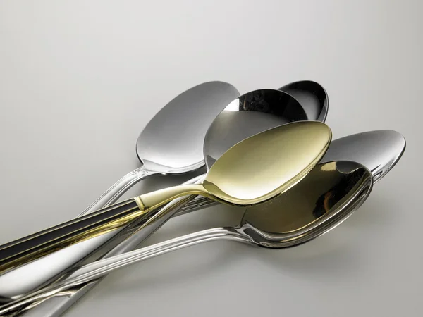 Cuchara dorada entre cucharas de plata — Foto de Stock