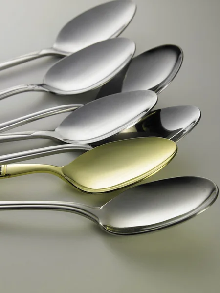 Cuchara dorada entre cucharas de plata —  Fotos de Stock