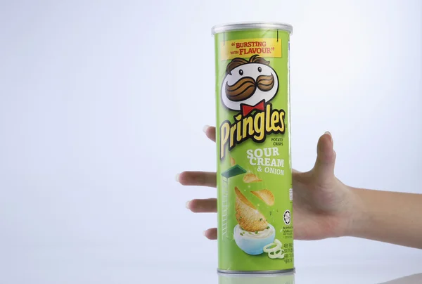 Hand holding a tube of the potato chips — Stock Photo, Image