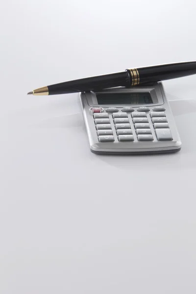 Calculadora y pluma sobre blanco — Foto de Stock