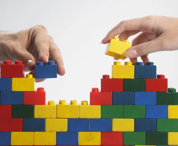 Duas mãos com blocos de construção coloridos — Fotografia de Stock
