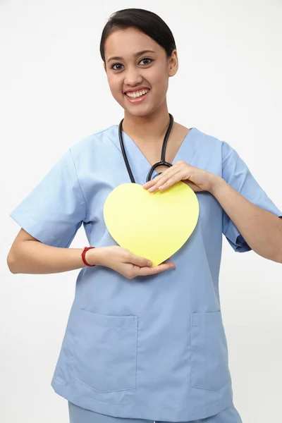 Graziosa infermiera che tiene il cuore giallo — Foto Stock