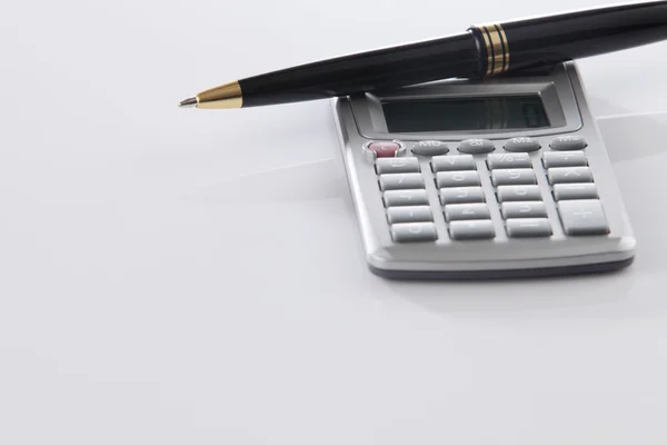 Calculadora y pluma sobre blanco — Foto de Stock