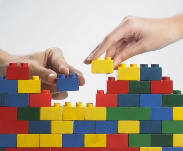 Duas mãos com blocos de construção coloridos — Fotografia de Stock