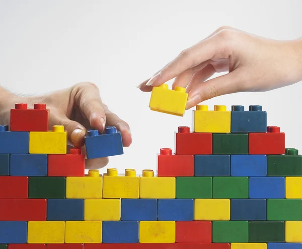 Dos manos con bloques de construcción de colores — Foto de Stock