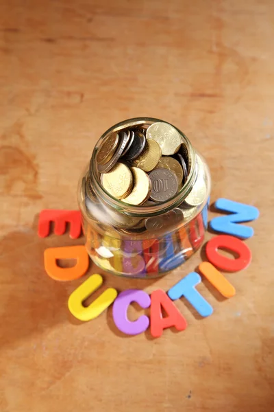 Moedas em jarra com sinal de educação — Fotografia de Stock