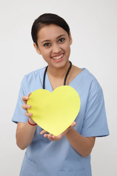 Graziosa infermiera che tiene il cuore giallo — Foto Stock