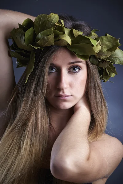 Studioporträt eines schönen Mädchens mit einer Krone aus Lorbeerblättern — Stockfoto