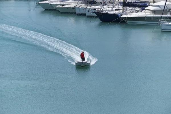 İtalya, Sicilya, Marina di Ragusa; 6 Haziran 2016, adam bir lastik tekne liman - yazı işleri