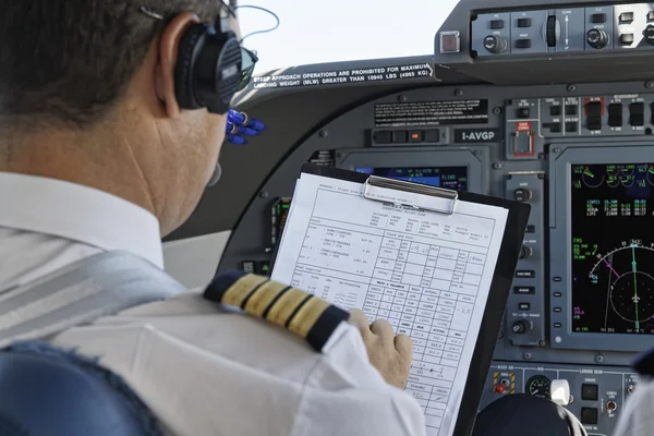 Италия, пилот проверяет свой план полета в кабине самолета — стоковое фото