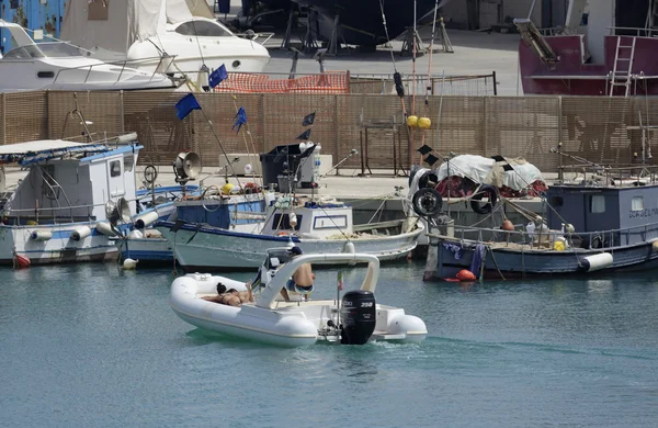 Italia, Sicilia, Mar Mediterraneo, Marina di Ragusa; 18 giugno 2016, persone a bordo di gommoni e pescherecci in legno e yacht di lusso a terra nel porto - EDITORIALE — Foto Stock