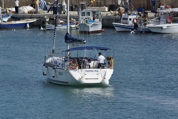 Italy, Sicily, Mediterranean sea, Marina di Ragusa; 23 June 2016, people on a sailing boat and wooden fishing boats in the port - EDITORIAL — Stock Photo, Image