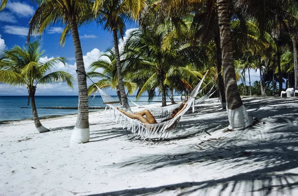 CUBA, Maria La Gorda beach; 25 March 2003, woman relaxing on an hammock under coconut palm trees - EDITORIAL (FILM SCAN) — Stock Photo, Image