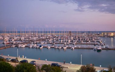 İtalya, Sicilya, Akdeniz, Marina di Ragusa (Ragusa Eyaleti); gün batımında limanda halk, motorlu tekne ve lüks yatlar 