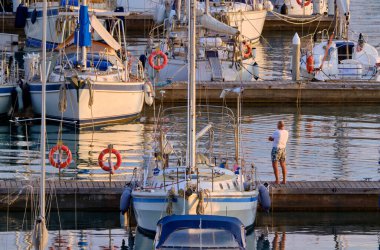 İtalya, Sicilya, Akdeniz, Marina di Ragusa (Ragusa Eyaleti); 11 Kasım 2020, limandaki insanlar ve yelkenliler - EDITORIAL