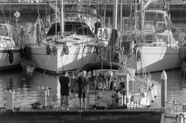 İtalya, Sicilya, Akdeniz, Marina di Ragusa (Ragusa Eyaleti); 15 Kasım 2020, limanda köpekli ve yelkenli tekneleri olan insanlar - EDITORIAL