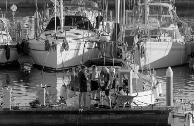 İtalya, Sicilya, Akdeniz, Marina di Ragusa (Ragusa Eyaleti); 15 Kasım 2020, limanda köpekli ve yelkenli tekneleri olan insanlar - EDITORIAL