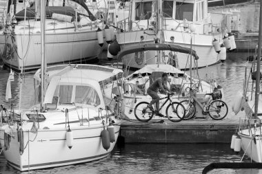 İtalya, Sicilya, Akdeniz, Marina di Ragusa (Ragusa Eyaleti); 16 Kasım 2020, limanda bisiklet ve lüks yatlarda bir adam - EDITORIAL