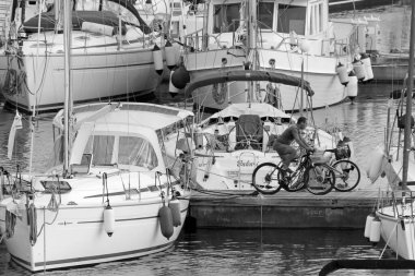 İtalya, Sicilya, Akdeniz, Marina di Ragusa (Ragusa Eyaleti); 16 Kasım 2020, limanda bisiklet ve lüks yatlarda bir adam - EDITORIAL