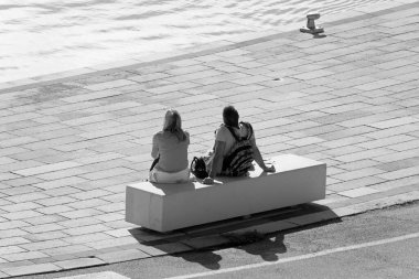 İtalya, Sicilya, Marina di Ragusa (Ragusa Eyaleti); limandaki bankta oturan çift 