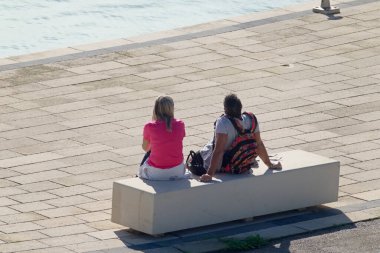 İtalya, Sicilya, Marina di Ragusa (Ragusa Eyaleti); limandaki bankta oturan çift 