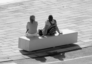 İtalya, Sicilya, Marina di Ragusa (Ragusa Eyaleti); limandaki bankta oturan çift 