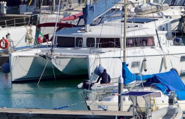 İtalya, Sicilya, Akdeniz, Marina di Ragusa (Ragusa Eyaleti); 22 Şubat 2021, limandaki kauçuk bir tekne ve lüks yatlarda adam - EDITORIAL