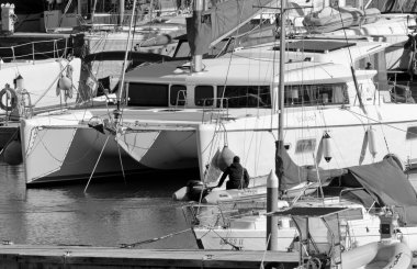 İtalya, Sicilya, Akdeniz, Marina di Ragusa (Ragusa Eyaleti); 22 Şubat 2021, limandaki kauçuk bir tekne ve lüks yatlarda adam - EDITORIAL