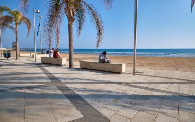 İtalya, Sicilya, Akdeniz, Marina di Ragusa (Ragusa Eyaleti), palmiye ağaçlarıyla deniz kenarında yaşayan insanlar. 