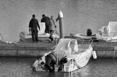 İtalya, Sicilya, Akdeniz, Marina di Ragusa (Ragusa Eyaleti); 26 Şubat 2021, limanda insanlar ve motorlu tekneler - EDITORIAL