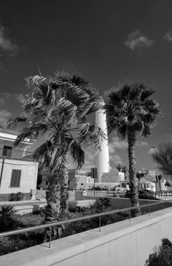 İtalya, Sicilya, Akdeniz, Punta Secca (Ragusa Eyaleti), deniz kenarındaki palmiyeleri ve deniz feneri manzaralı binalar.