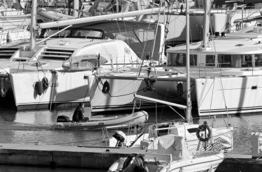 İtalya, Sicilya, Akdeniz, Marina di Ragusa (Ragusa Eyaleti); 22 Şubat 2021, limandaki kauçuk bir tekne ve lüks yatlarda adam - EDITORIAL