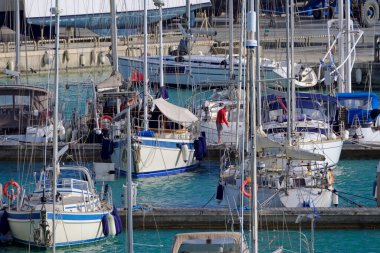 İtalya, Sicilya, Akdeniz, Marina di Ragusa (Ragusa ili); 17 Mart 2021, limandaki insanlar ve yelkenliler - EDITORIAL