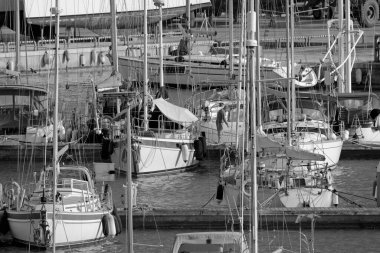 İtalya, Sicilya, Akdeniz, Marina di Ragusa (Ragusa ili); 17 Mart 2021, limandaki insanlar ve yelkenliler - EDITORIAL